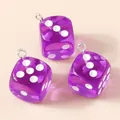 Détail macro de pendentifs dés en résine violette translucide avec anneaux argentés sur beige - Violet