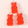Close-up of translucent red resin gummy bear charms with silver metal jump rings - Red