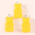 Detailed view of three yellow resin gummy bear charms with silver metal rings for DIY jewelry - Yellow