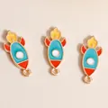 Macro shot of three colorful cartoon rocket enamel alloy charms for DIY jewelry making - Blue