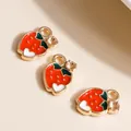 Macro view of strawberry-shaped alloy charms with a green leaf and gold-plated setting - Red