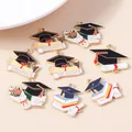 Macro shot of assorted graduation alloy charms with enameled graduate hat and scrolls - Mixed