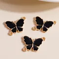 Macro detail of black enamel butterfly charms with gold trim and dual connection rings - Black
