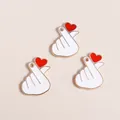 Macro detail of three heart-gesture enamel pendants with gold edges for DIY jewelry - White