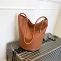 Schicke karamellbraune Lederbeuteltasche auf einem Koffer, ideal für den Arbeitsweg - Braun