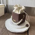 Detail of coffee woven bucket bag with pearl handle and cream drawstring lining - Coffee