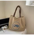 Detail of khaki canvas tote bag with blue LMD embroidery on white office desk - One Size / Khaki