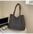 Detail of grey canvas tote bag with leather straps and blue circular embroidery on a desk - One Size / Dark Brown