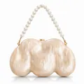 Detail of shell-shaped acrylic clutch with marble texture and large pearl handle - Apricot