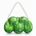 Close-up of emerald green marbled acrylic clutch with elegant white pearl handle - Green