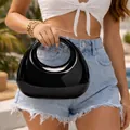 Borsa a mano a mezzaluna in acrilico nero lucido in un contesto di moda all'aperto - Nero