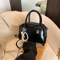 Glänzende schwarze quadratische Handtasche mit modischem Text, Perlenanhänger und Gurt - Mit Anhänger / Schwarz