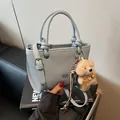 Sac à main bleu tissé avec poignée nouée, logo lion doré et charme de doudou ours - Bleu Avec Pendentif Ours