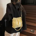 Quilted yellow bucket bag with golden chain strap shown in a fashionable street style - Small / Yellow