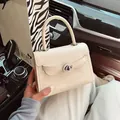 Cream-colored square handbag featuring cartoon embossing and silver turn-lock clasp - White