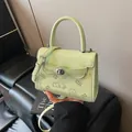 Mint green crossbody bag with cartoon prints and silver buckle on a leather sofa - Green