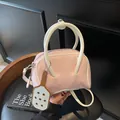 Pink and white Boston style handbag with contrast stitching and charm on dark background - Pink