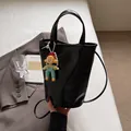 Minimalist black glossy bucket bag with cartoon charm and detachable shoulder strap - Small / Black