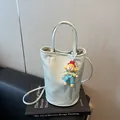 Lichtblauwe emmertas met cartoon hanger en parelketting op een boek achtergrond - Klein / Meer Groen
