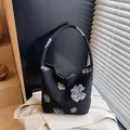 Chic black canvas bucket bag featuring a large white floral pattern and single handle - Black