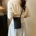 Minimalist black litchi texture crossbody phone bag with slim strap shown on model - Black