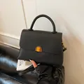 Elegant black lychee textured leather handbag with gold metal clasp and crossbody strap - Black