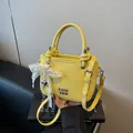 Sac seau jaune vif avec texture litchi, logo en métal et breloque coeur en perle - Style Charme Noeud / Jaune