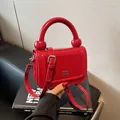 Minimalistische rode leren handtas met uniek handvat en metalen logo-accent - Bordeauxrood