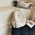Minimalist beige nylon backpack with many pockets and woven patch on a blue chair - Off White
