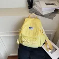 Minimalist yellow nylon backpack featuring buckle closure and front zipper pocket - Yellow