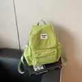 Minimalist light green nylon backpack with white label on black leather sofa - Green