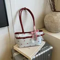 Sac crème à motif nœuds rouges et breloques cœur sur une valise métallique argent - Bleu