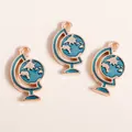 Trois pendentifs globe dorés avec émail bleu et anneaux de suspension sur fond beige - Bleu