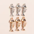 Detailed view of silver and gold fishbone charms with sparkling rhinestones and black eyes - Multicolor