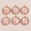 Nahaufnahme von rosa Emaille-Schmetterlingsanhängern mit Goldbasis und Strasssteinen - Rosa