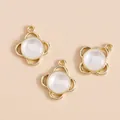 Detail van drie klavervormige gouden bedels met witte kattenoogstenen voor DIY-sieraden - Goud