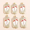 Detail of alloy paw print charms with white and red enamel on a light beige backdrop - Gold