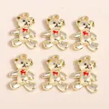 Detailed macro view of 6 golden alloy bear pendants with red bows and hanging loops - Gold