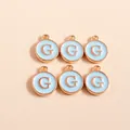 Macro shot of 6 light blue enamel round pendants with rose gold letter G for DIY jewelry - Letter G