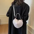Bolso bandolera rosa claro con forma de corazón y acabado brillante usado por una modelo - Rosa