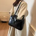 Bolso tote negro brillante de cuero sintético con correa de hombro mostrado en modelo - Negro