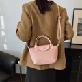Pink dumpling style shoulder bag with woven texture and adjustable strap on a model - Pink