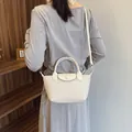 Mini dumpling bag in cream white with woven texture, featuring top handle and strap - Off-white