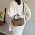 Brown woven texture dumpling bag with leather handle and shoulder strap in variant finish - Brown