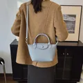 Gray-blue woven texture crossbody bag with shoulder strap worn over a wool coat - Blue