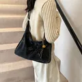 Black velvet hobo bag with woven strap and gold bell charm worn by model on stairs - Black With Rabbit Pendant