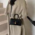 Chic black patent leather handbag with gold hardware and a rectangular top handle design - Black