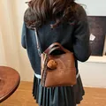 Brown bucket bag for women with plush bear charm and crossbody strap worn by a model - With Pendant / Brown