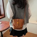 Chic brown PU leather bucket bag with gold buckle worn by model in a minimalist setting - 21*10*18 / Brown