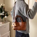 Sac seau tressé marron avec breloque lion porté par un mannequin dans un décor intérieur - Avec Pendentif / Marron